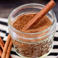 homemade pumpkin pie spice in a jar with a cinnamon stick