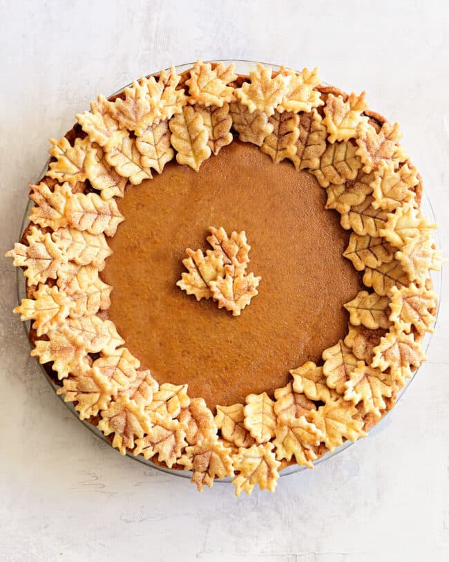 a whole pumpkin pie with leaf cut-outs