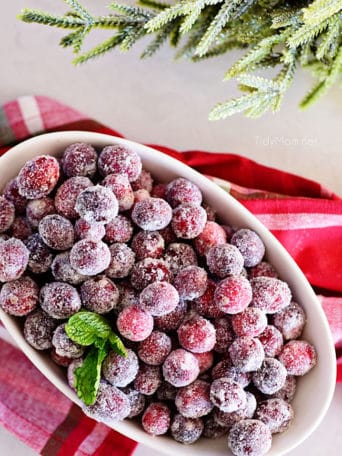 sugared cranberries in an oval bowl with Christmas napkin