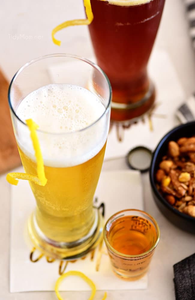 beer cocktail with a lemon twist next to a bowl of nuts