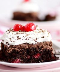 a piece of chocolate covered cherry cake with whipped cream on top