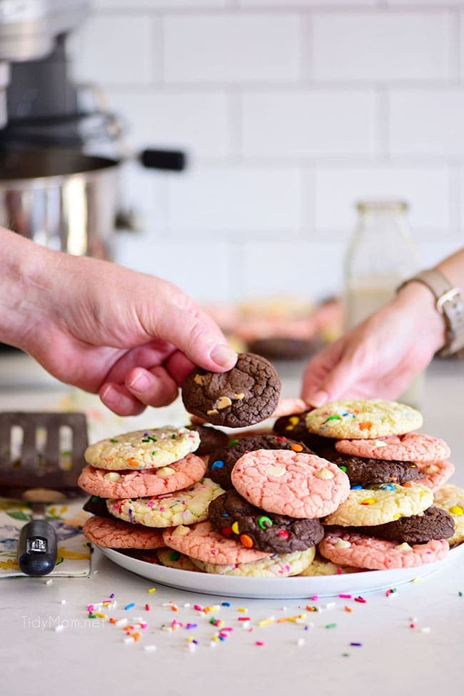 2 people grabbing a cookie off a tray of cookies