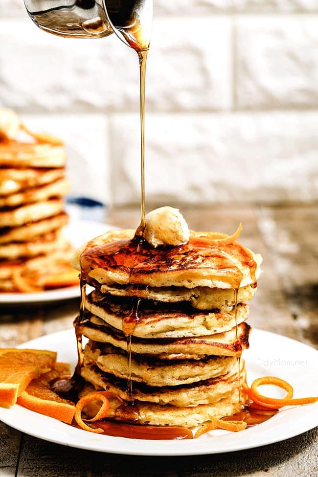 stack of pancakes with syrup being drizzled over the top
