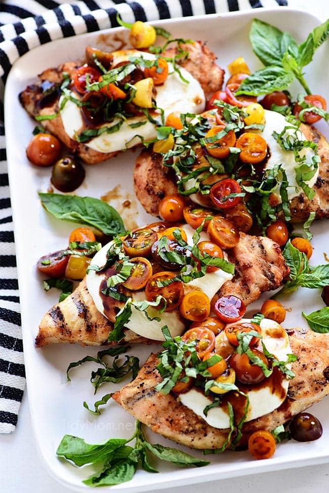 platter of grilled chicken breasts topped with caprese salad