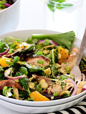 asian chicken salad in a white bowl with a fork