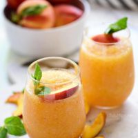Two frozen peach cocktails in stemless wine glasses