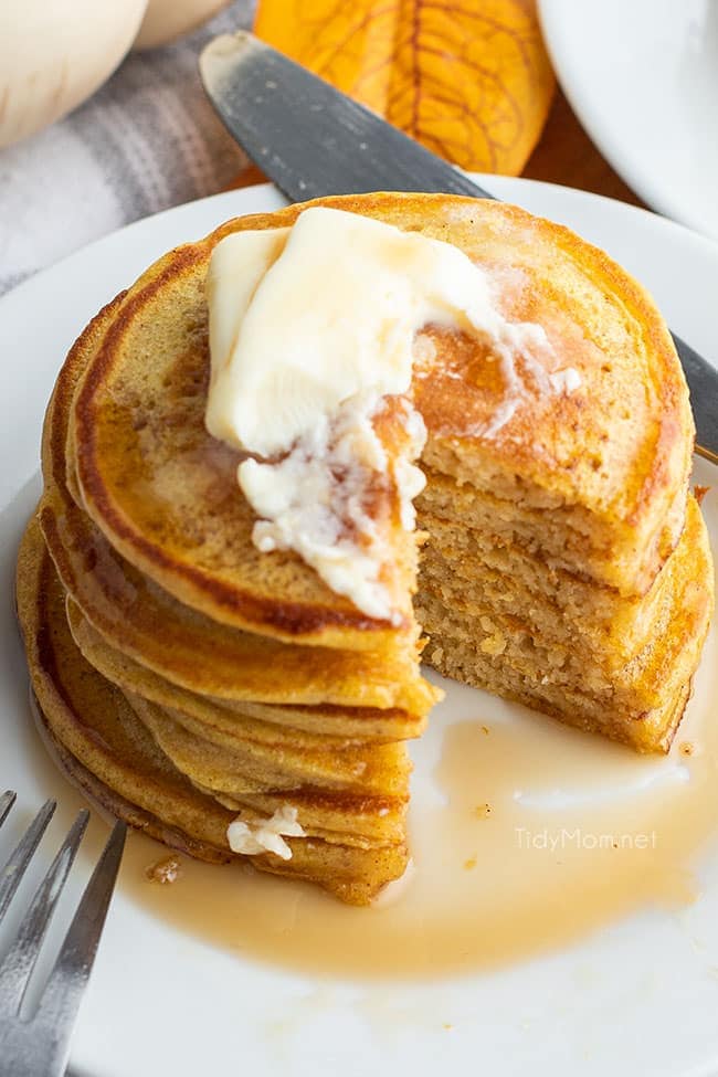 Cut stack of pancakes on plate with syrup