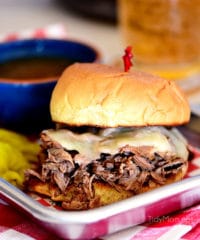 Italian beef sandwich with cheese and a bowl of au jus