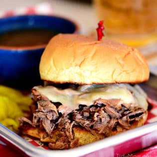 Italian beef sandwich with cheese and a bowl of au jus