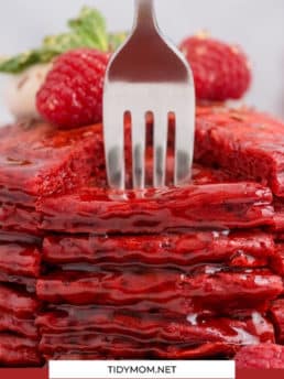 a stack of red pancakes with a form stabbing in them