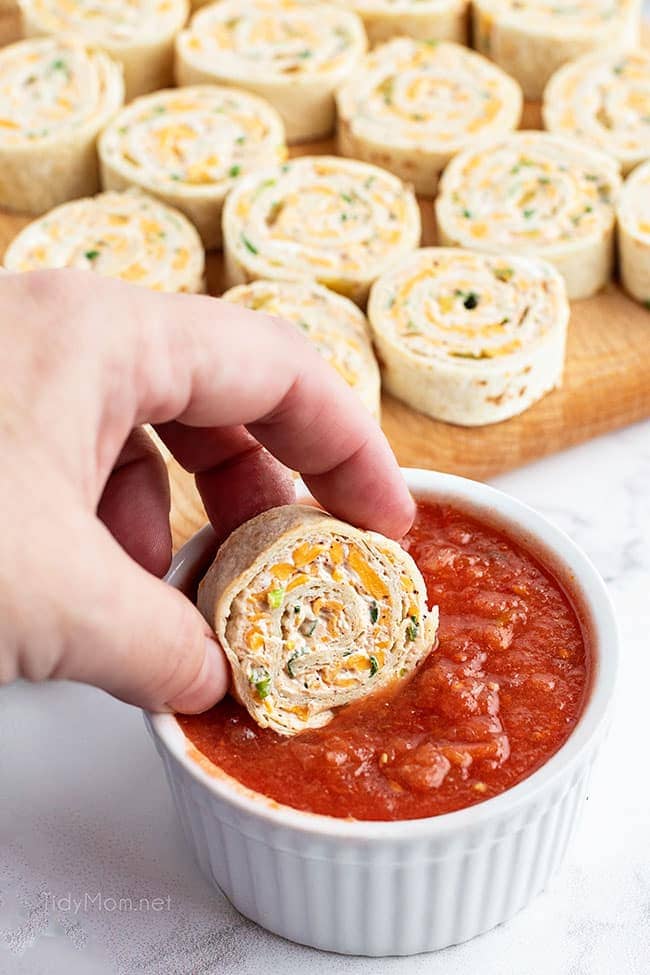dunking a pinwheel appetizer in red sauce