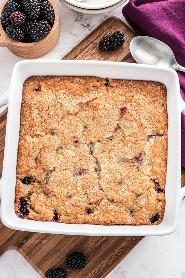 blackberry cobbler in a baking dish with a purple napkin