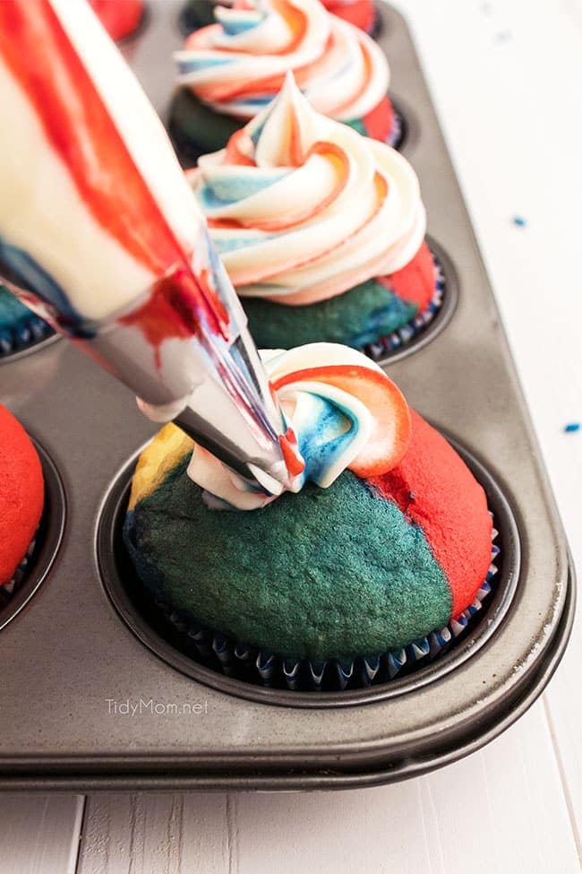 decorating a red white and blue cupcake with frosting in a piping bag