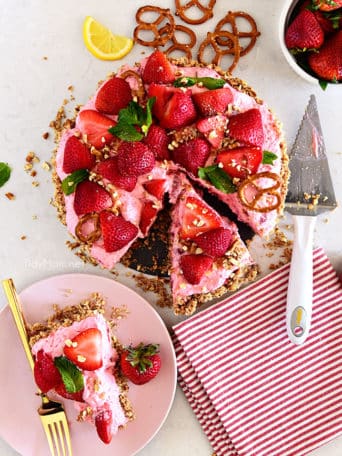 strawberry pretzel pie cut with a slice on a pink plate