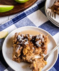peanut butter apple bread pudding on a white plate with a blue checked napkin