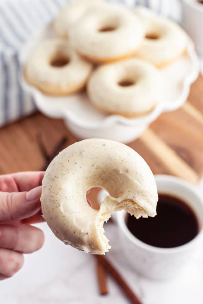 cinnamon donut with a bite missing over a cup of coffee