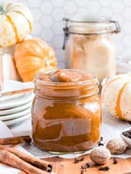pumpkin butter in a jar with pumpkins on the counter