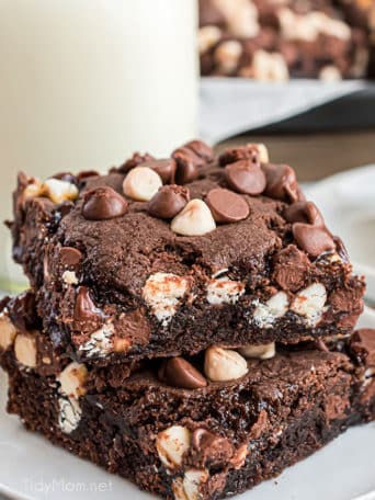 2 chocolate caramel bars stacked on a plate with glass of milk