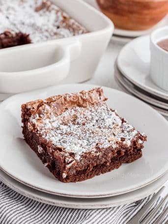 Nutella gooey butter cake on a white plate next to the cake pan