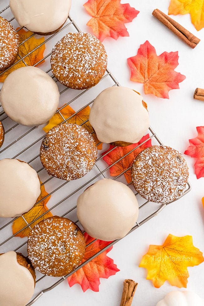 glazed and powdered sugar topped pumpkin muffins on a cooling rack