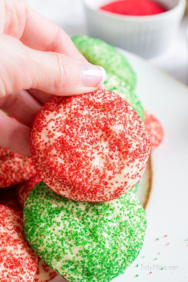 womans hand holding a red Christmas drop sugar cookie