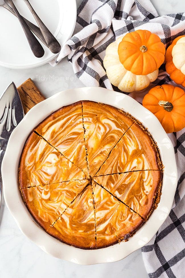 pumpkin cheesecake pie in a white dish and sliced