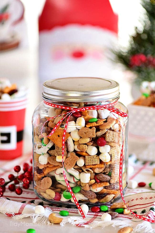 Christmas snack mix in a jar with a lid and a red ribbon