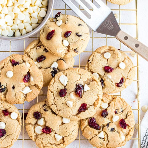 cranberry cookies on a gold cooling rack with spatula