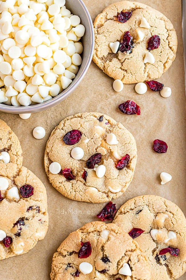cranberry cookies on brown parchment paper with white chocolate chips in a bowl