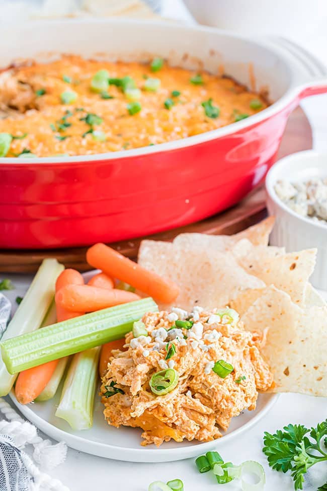 cheesy buffalo chicken dip on a plate with veggies and chips