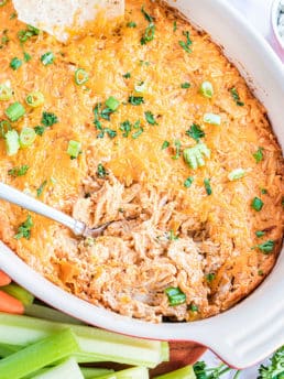 baked buffalo chicken dip in a white dish with a spoon