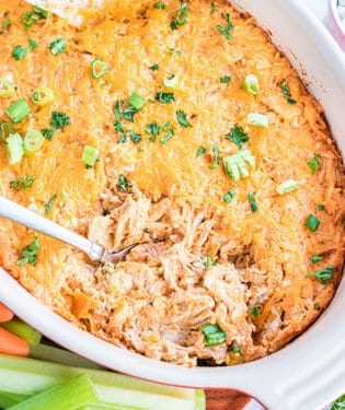 baked buffalo chicken dip in a white dish with a spoon