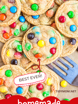 a pile of M&M cookies with a spatula