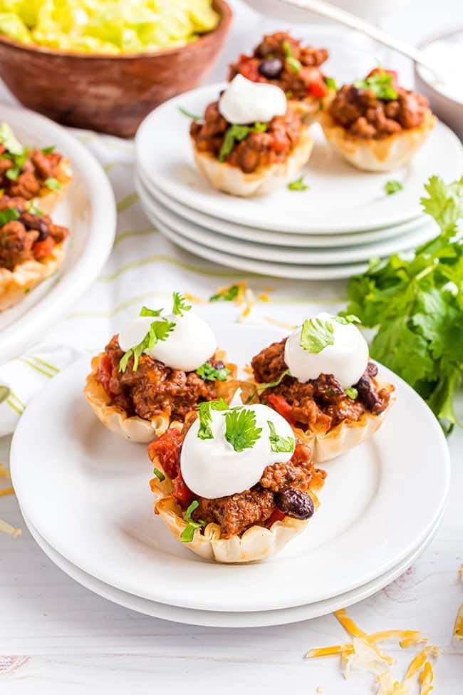 phyllo cup taco bites topped with sour cream on white plates