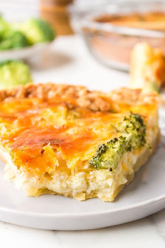 broccoli cheddar quiche with bite missing on grey plate