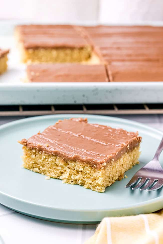 Peanut butter sheet cake on a plate in front of the pan
