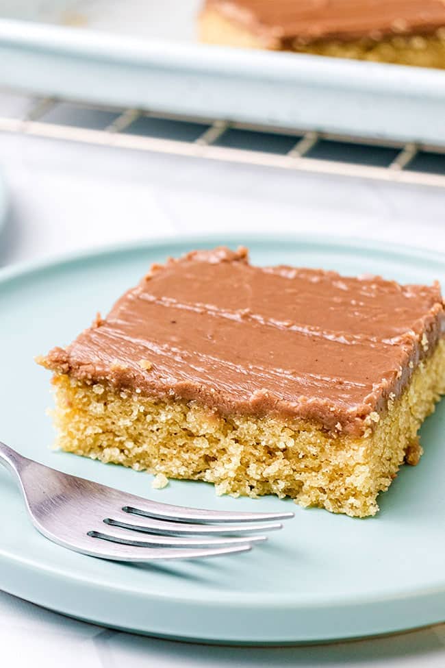Peanut butter sheet cake with chocolate frosting on a blue plate with a fork