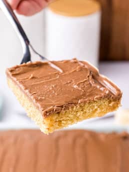 Slice of peanut butter sheet cake with chocolate frosting on a spatula