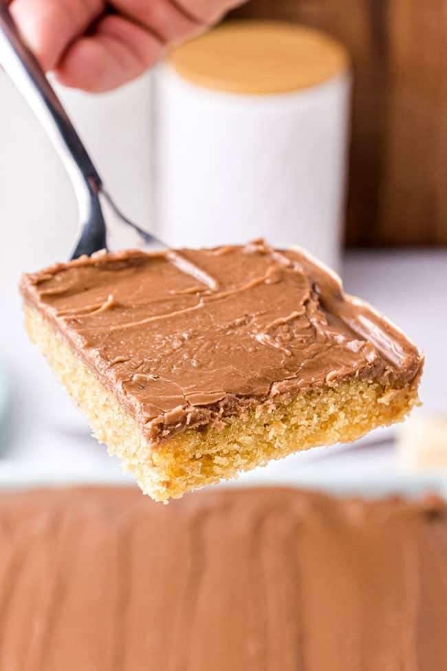 Slice of peanut butter sheet cake with chocolate frosting on a spatula
