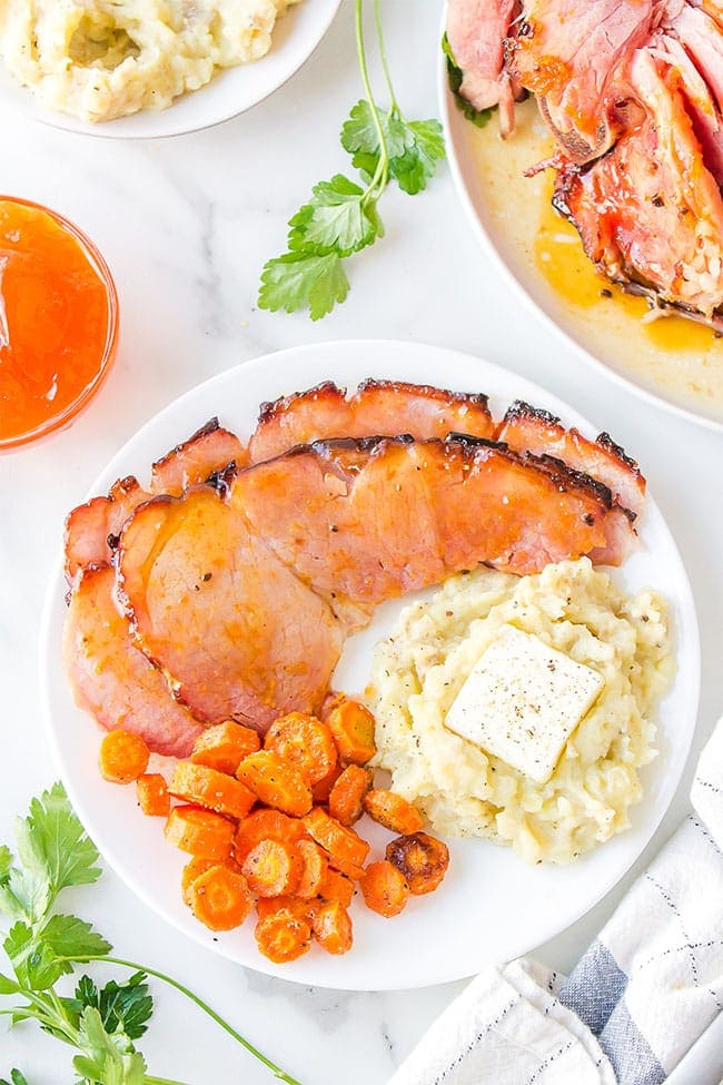 Honey Glazed Ham With Apricot on a plate with carrots and mashed potatoes