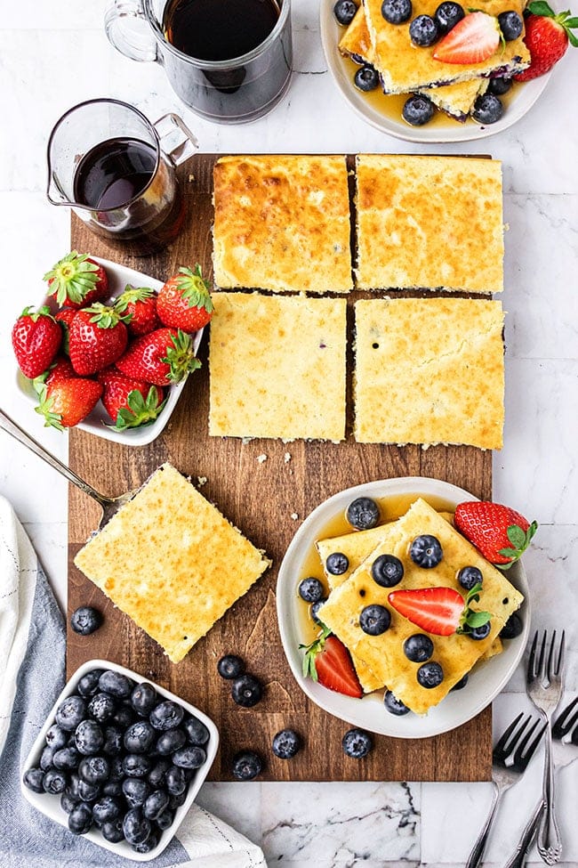 sheet pan pancakes with bisquick on a wood board and plated with fresh fruit