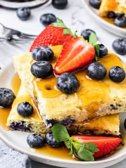 a stack of oven baked pan sheet pancakes on a plate with fresh berries