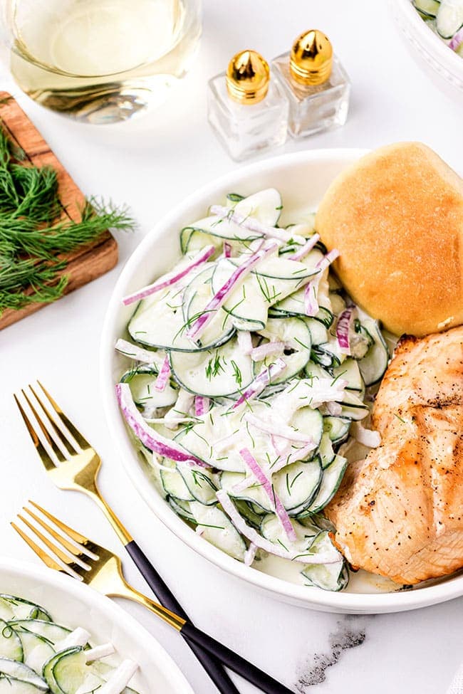 creamy cucumber salad side dish on a plate with chicken 