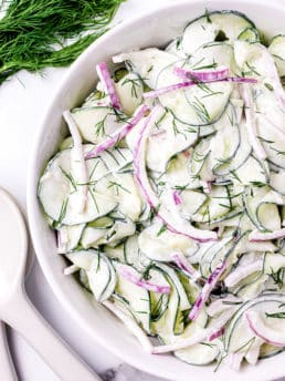 creamy cucumber and onion salad in a white serving bowl