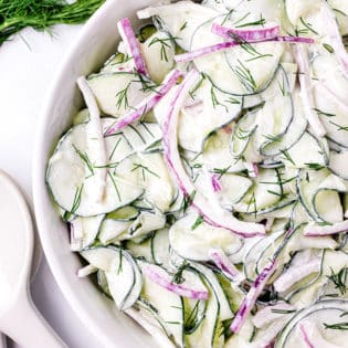 creamy cucumber and onion salad in a white serving bowl