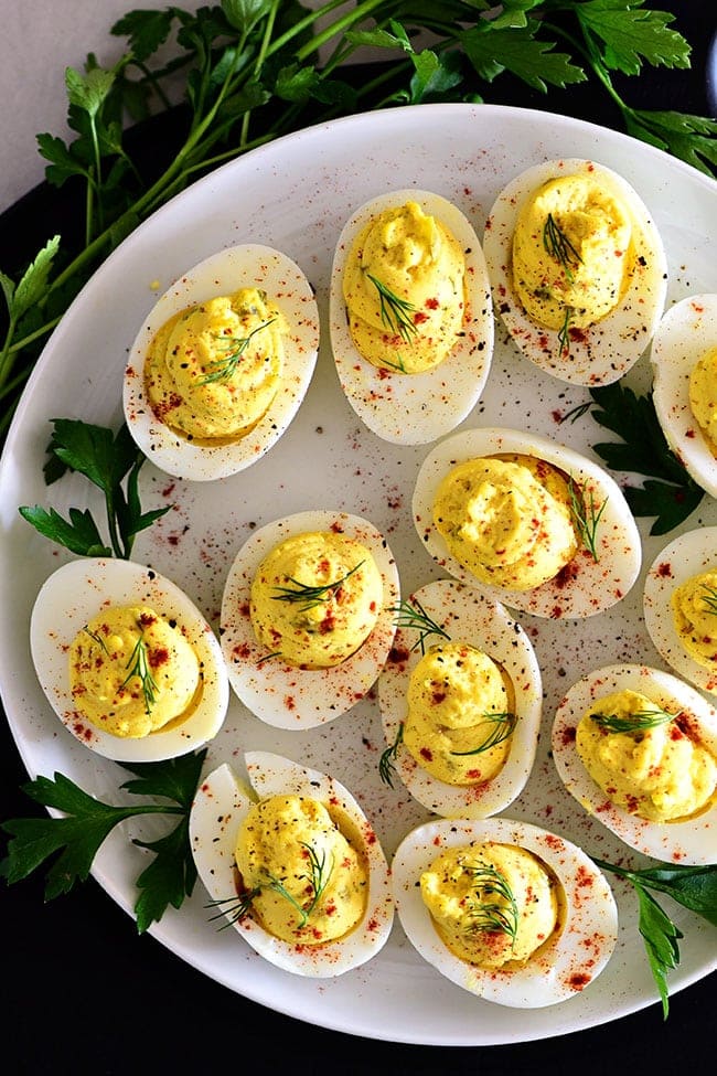 Classic deviled eggs on a white plate with fresh dill garnish