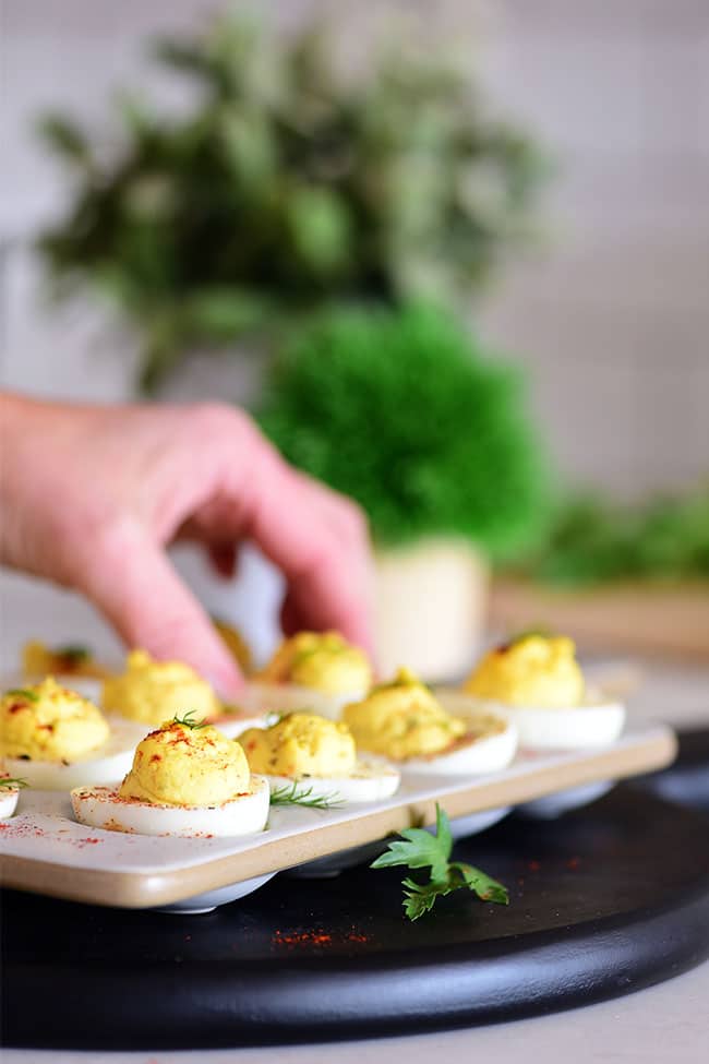 hand reaching for a deviled egg off a platter