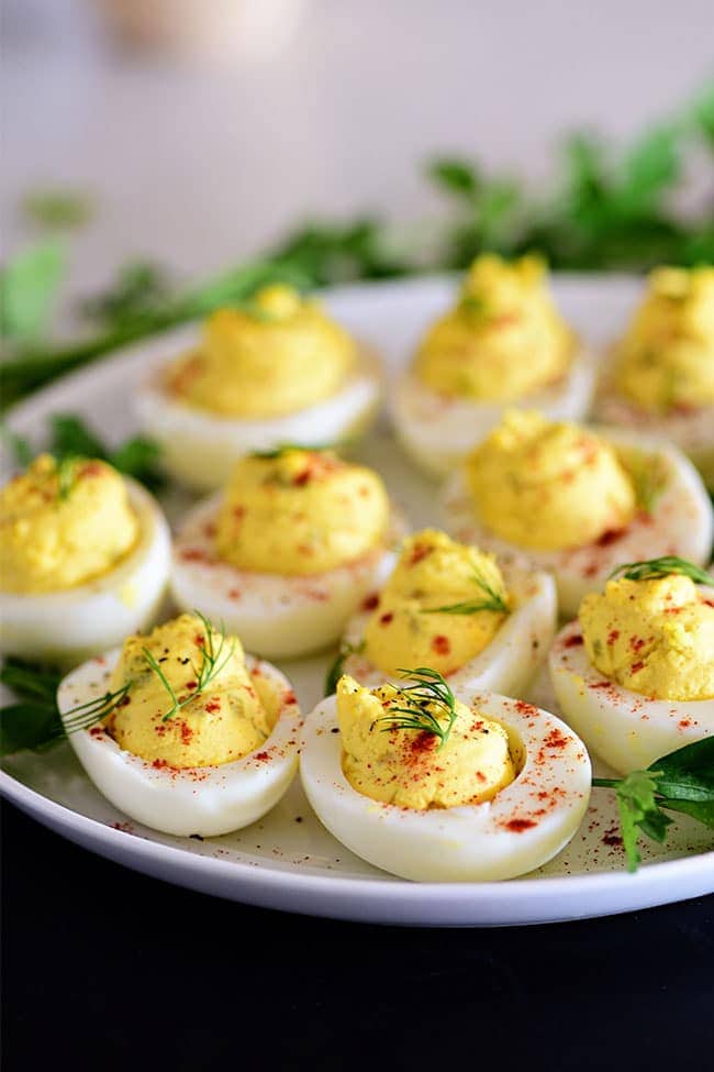 Easy deviled eggs on a white plate with fresh dill garnish