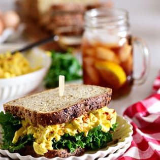 classic egg salad sandwich with a glass of iced tea and red checked napkin