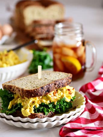 classic egg salad sandwich with a glass of iced tea and red checked napkin